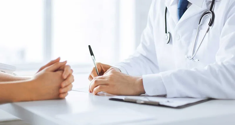 Doctor sitting across from patient with clipboard and pen