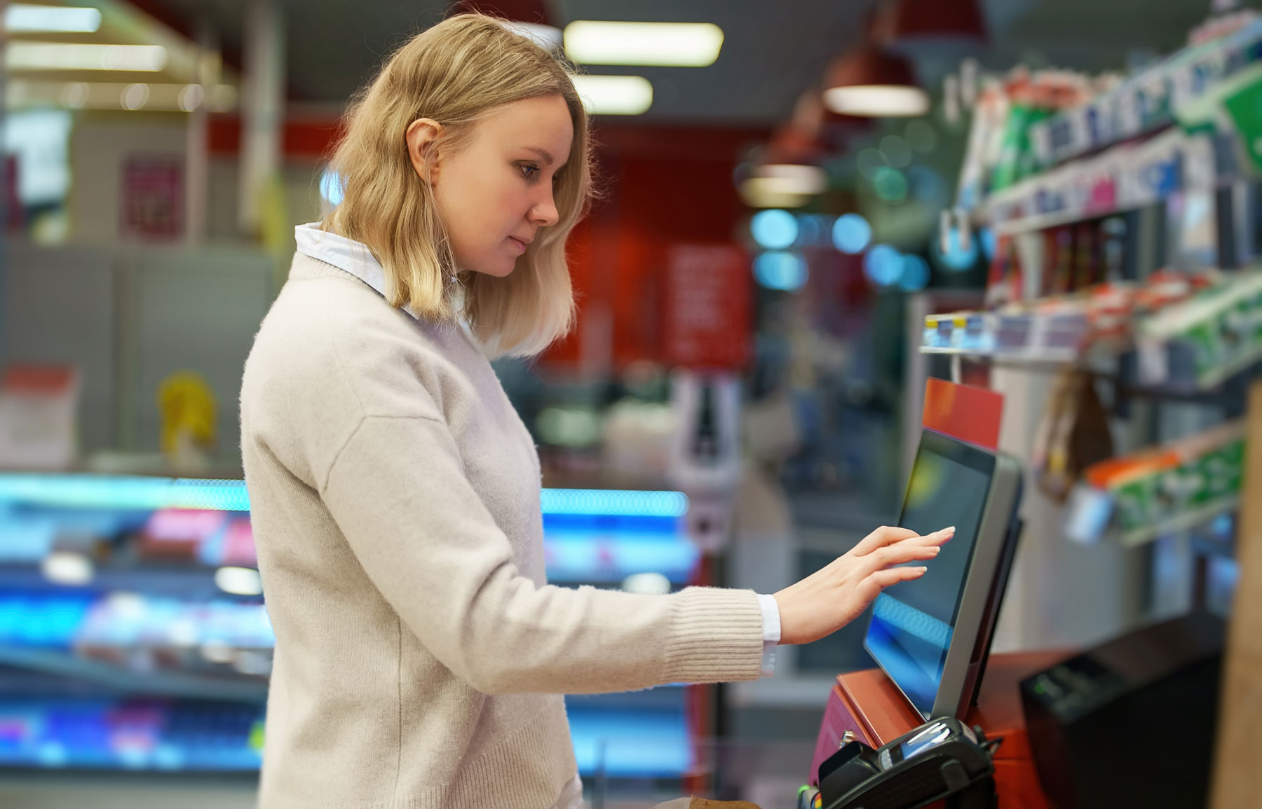 Woman pays at self-checkouts in supermarket