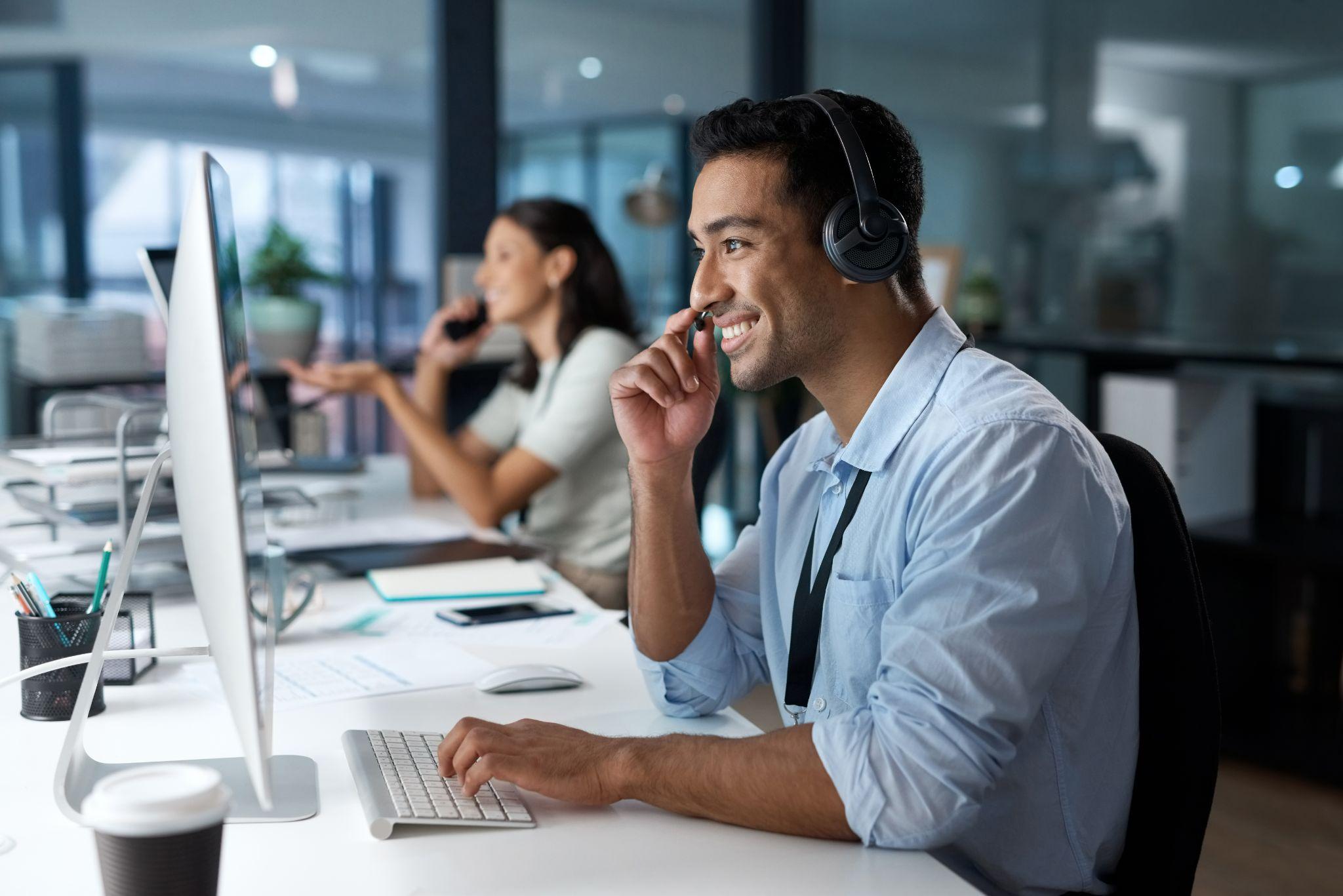 smiling-MSP-employee-with-headset-typing-on-computer-speaking-with-customer-to-resolve-needs